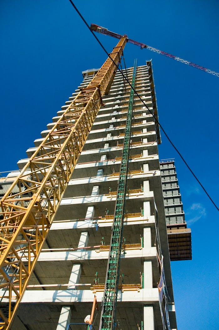 Mastering the First Impression: Your intriguing post title goes here Low-angle view of skyscraper under construction with crane, clear blue sky.